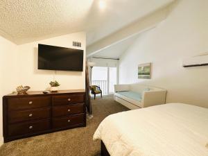 彭萨科拉海滩Gulf Front Penthouse Condo的一间卧室配有一张床和一个带平面电视的梳妆台。