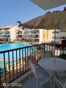 萨尔雷Solaren Apartments Boavista的阳台配有桌子、遮阳伞和游泳池。