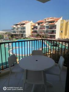 萨尔雷Solaren Apartments Boavista的一个带游泳池的阳台,配有一张白色的桌子和椅子