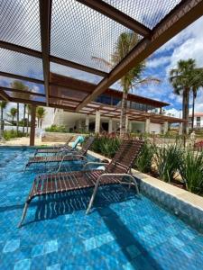 皮雷诺波利斯Suites Quinta Santa Barbara的游泳池里摆放着三把椅子,设有围栏