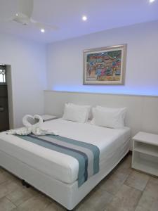 安塞奥潘拉茹舍特酒店的卧室配有一张白色床,墙上挂有绘画作品