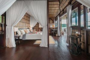 Pulau BiriePapua Paradise Eco Resort的卧室配有白色窗帘的床