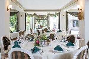 克卢日-纳波卡阳光花园高尔夫及Spa度假酒店的一间设有白色桌椅和窗户的用餐室