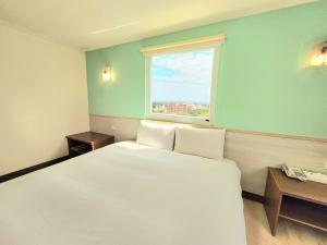 台东苹果商务旅店的卧室设有一张白色大床和一扇窗户。