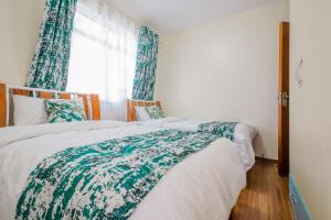 内罗毕Tropical themed 3BR and DSQ Apartment的一间卧室设有两张床,窗户配有窗帘