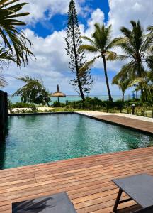 贝尔马尔Tropical beachfront apartment的一个带木甲板和棕榈树的游泳池
