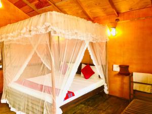 锡吉里亚Sungreen Cottage Sigiriya的卧室配有带白色窗帘的天蓬床