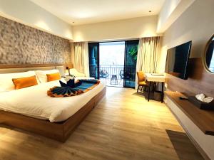 芭东海滩Amalthea Hotel的一间卧室配有一张带电视和书桌的床。