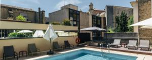 蒙彼利埃都会大洋洲酒店的一座大楼内的游泳池,配有椅子和遮阳伞