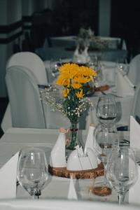 德辛尤卡普尔酒店的一张桌子,上面有酒杯,花瓶上还有黄色的花