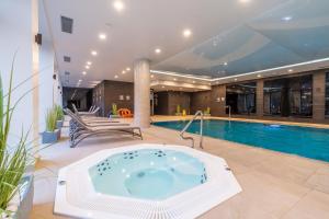 科沃布热格Apartamenty Fenomen - Horizon, Nadmorskie Tarasy FREE PARKING, SWIMMING POOL, SAUNA AND OTHER!的一座房子内带热水浴池的游泳池