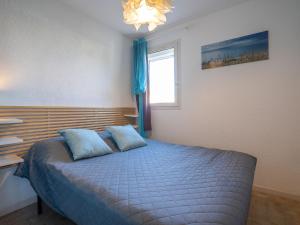 勒格罗-迪鲁瓦Apartment Les Caraïbes-1 by Interhome的一间卧室配有一张带蓝色枕头的床和一扇窗户。