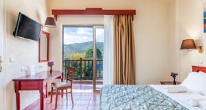 斯科派洛斯Rigas Hotel Skopelos的酒店客房设有一张床、一张书桌和一个阳台。