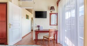 斯科派洛斯Rigas Hotel Skopelos的配有桌椅和电视的房间