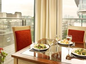 伦敦Marlin Apartments London Bridge - Empire Square的一张桌子,上面放着两盘食物和酒杯