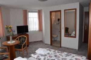 申海德Hotel Carola的酒店客房配有床、桌子和镜子