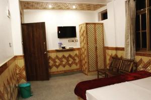 西姆拉The MoonLight Stay - Shimla的一间卧室配有一张床、一台电视和一把椅子