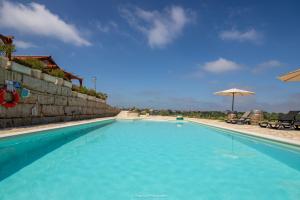 巴塔拉The Olive Hill Guesthouse的一个带遮阳伞的大型蓝色游泳池