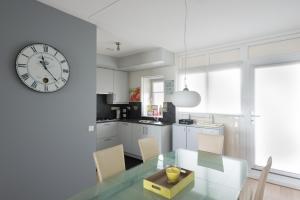 布雷斯肯斯Hello Zeeland - Appartement Port Scaldis 19-042的厨房配有玻璃桌和墙上的时钟