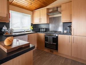 金罗斯Chalet Loch Leven Lodge 4 by Interhome的厨房配有木制橱柜和炉灶烤箱。
