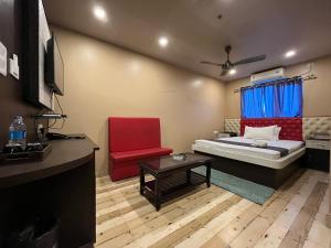 古瓦哈提The Rhino的小房间设有一张床和一把红色椅子