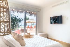 卡约港Tanusas Retreat & SPA的一间卧室配有一张床,阳台配有遮阳伞