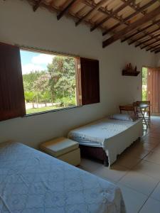 里奥迪孔塔斯Chale Trilha Das Aguas的一间卧室设有两张床和大窗户