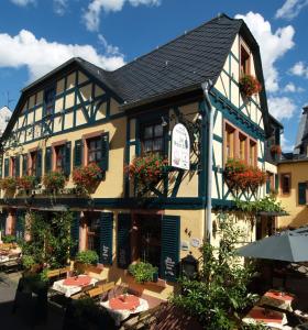 吕德斯海姆Weinhotel des Riesling Zum Grünen Kranz的前面设有桌椅的建筑