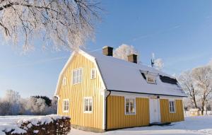 蒂达霍尔姆Amazing Home In Tidaholm With Kitchen的屋顶上积雪的黄色房子
