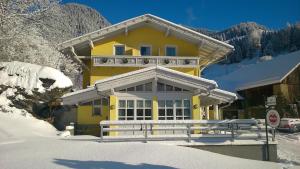 马尔尼茨Pension Siegelbrunn B&B的雪中带围栏的黄色房子