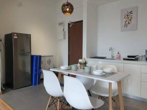 关丹Best Moments Studio City - Imperium Residence的厨房配有带白色椅子的桌子和冰箱。