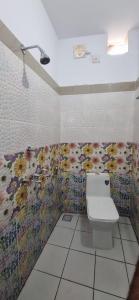 RānīSKR Gusto Inn的浴室配有卫生间,墙上挂有鲜花