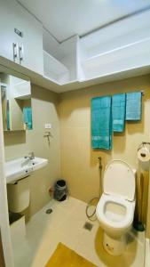 马尼拉Cozy 1Br with Netflix & Balcony Pool View Condo的浴室设有卫生间、水槽和蓝色毛巾