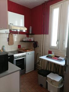 希农La Boussole - Maison meublée 3 chambres 6 pers.的厨房设有红色的墙壁、炉灶和窗户。
