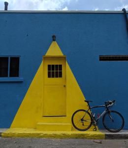 金斯敦Ragamuffin Hostel的停在一座黄色门的建筑旁边的自行车