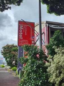 新普利茅斯兰德马克庄园酒店的灌木丛前的红色标志