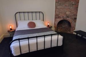本迪戈Heritage Cottage in the heart of Bendigo的一间卧室配有一张带砖砌壁炉的床