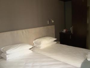 伊登维尔Bergliot Guest House的一张带白色床单和枕头的床