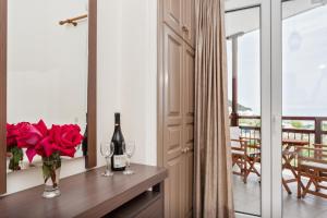 斯科派洛斯Akti Fine Rooms的一间设有一张桌子的房间,配有一瓶葡萄酒和玫瑰