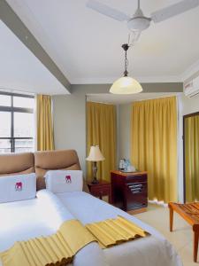 姆万扎LEYSHOF HOTEL的卧室配有一张白色大床和黄色窗帘