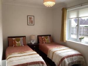 灵伍德Forest Heath Holidays - Denphyl的带窗户的客房内的两张床