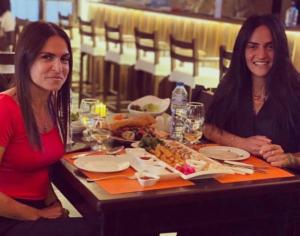马达巴Mount Nebo Hotel & Restaurant Madaba City Center的两个坐在餐桌上,拿着一盘食物的女人