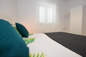 曼德雷Lavanda的一张带绿色枕头的白色床和窗户