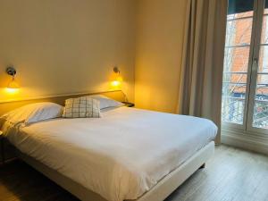 奥尔良Hôtel Marguerite的卧室配有一张带两个枕头的大白色床