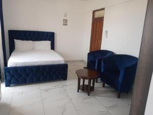 蒙巴萨Amber Apartment的一间卧室配有一张床、一张蓝色的沙发和椅子
