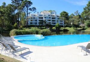 埃斯特角城Departamento con jardin en Green Park, Punta del Este的一座带躺椅的大型游泳池和一座建筑
