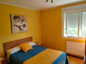 Bembribe纽弗阿隆索旅馆的一间卧室设有一张黄色墙壁和窗户的床