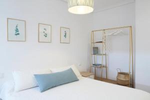 希洪Apartamento con terraza a un paso de la playa的卧室配有白色的床和镜子