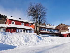 贝特斯托尔格诺伦斐杰拉德酒店的树旁的一座红色建筑,被雪覆盖着