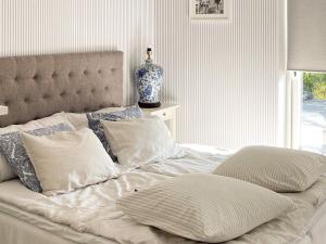 埃勒斯Holiday home ELLÖS IX的一张带枕头的白色床和一个窗户上的花瓶